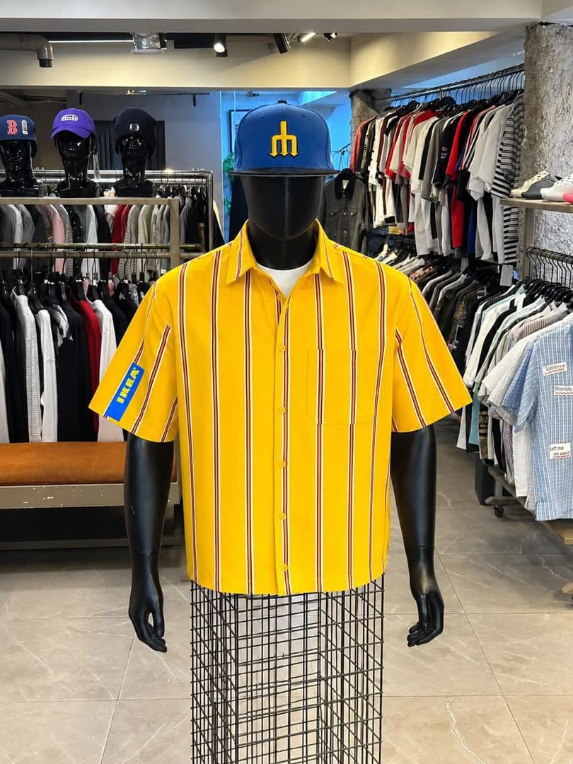 Yellow striped short sleeve button-up shirt on mannequin with blue sleeve patch.