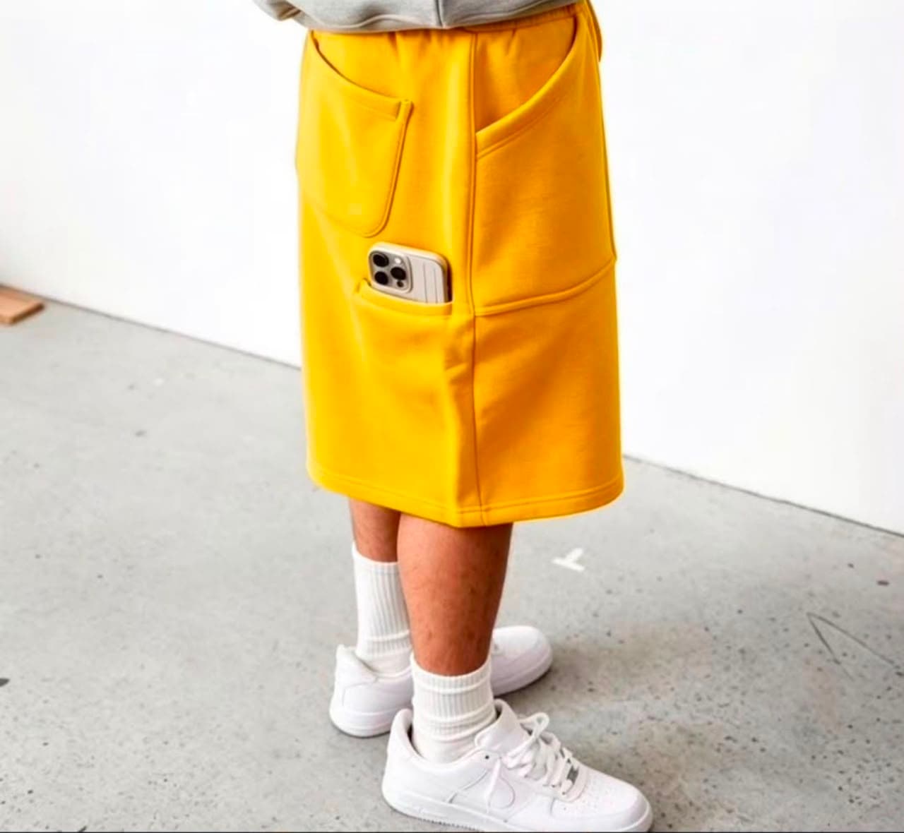 Model wearing yellow 3/4 fleece shorts with phone in side pocket.