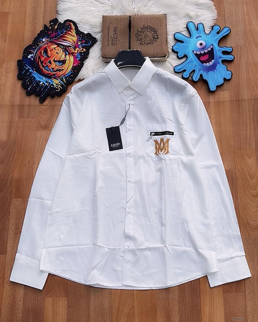 White Amiri monogram long sleeve shirt with zip pocket laid flat.