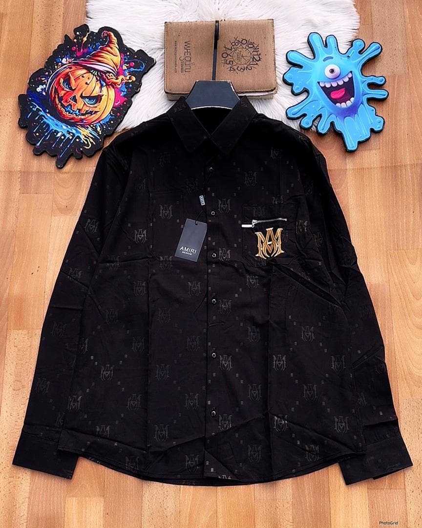 Black Amiri monogram long sleeve shirt with zip pocket laid flat.