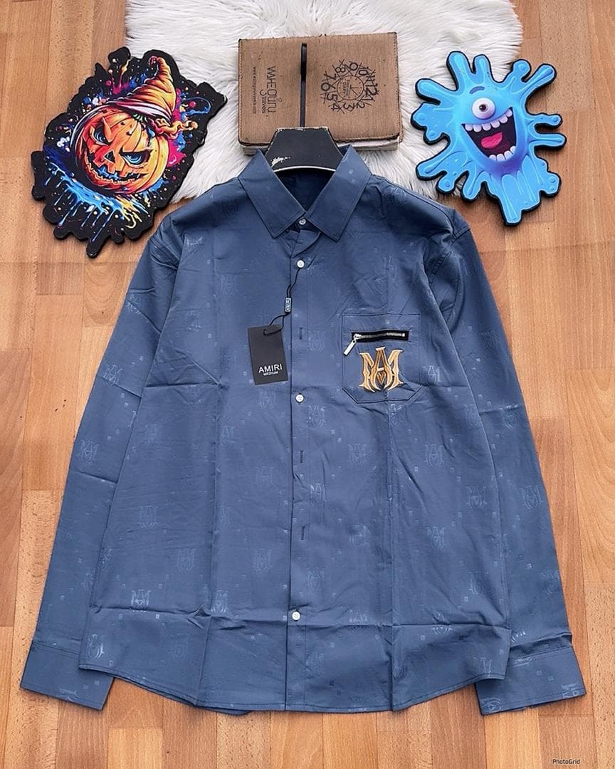 Blue Amiri monogram long sleeve shirt with zip pocket laid flat.