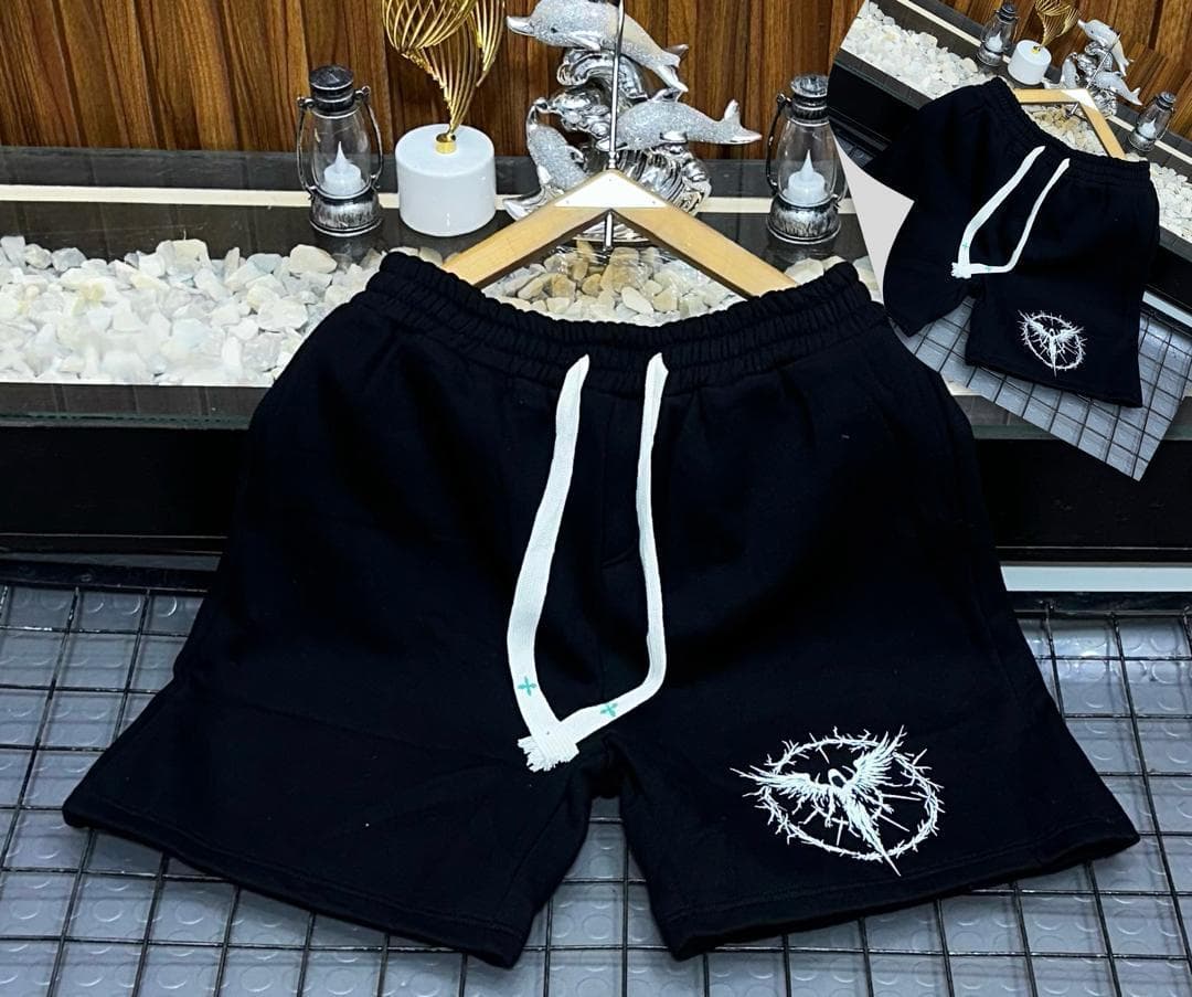 Black fleece shorts with white thorn bird circular embroidery on leg.