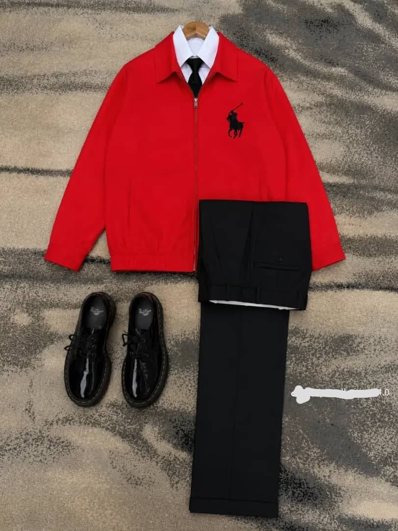 Red polo zip jacket with white shirt, black tie, black trousers and shoes.