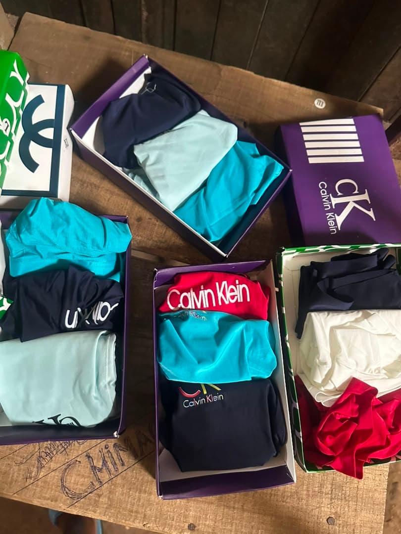 Assorted Calvin Klein boxer briefs in various colors displayed in boxes on wooden table.