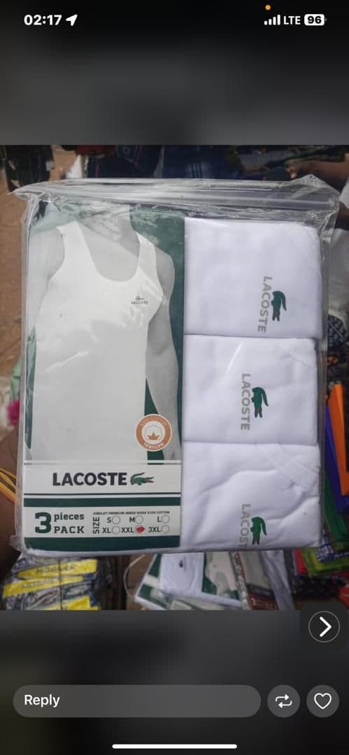 Lacoste 3-piece pack of white singlets in plastic packaging displaying branding, logo, and available sizes.