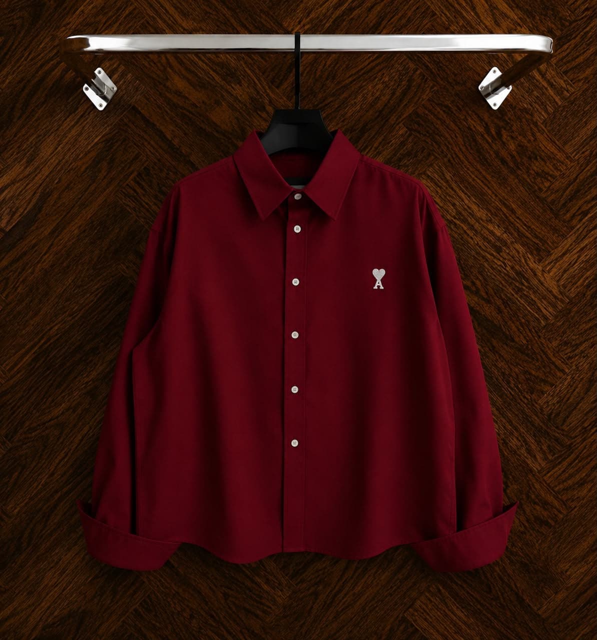 Burgundy button-down shirt with chest embroidery on wooden background.