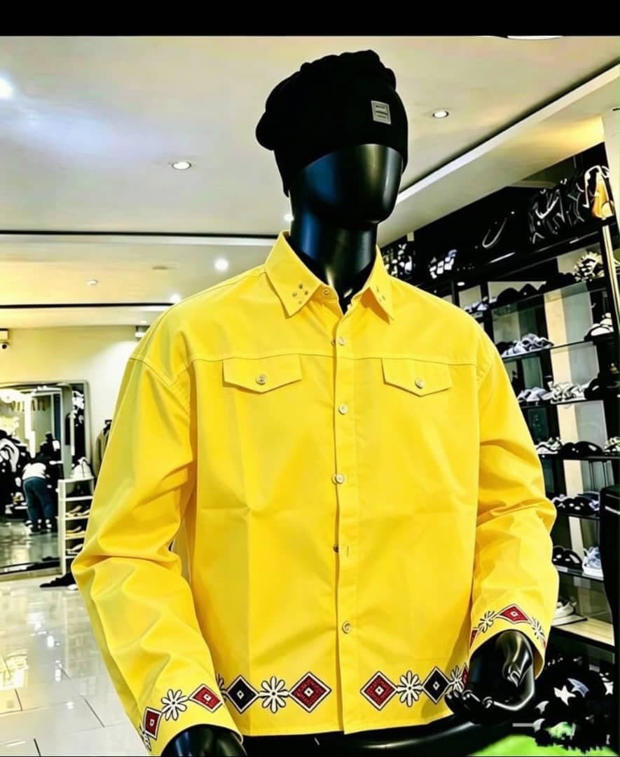 Yellow long sleeve button-up shirt with embroidery on cuffs and hem, shown on mannequin.