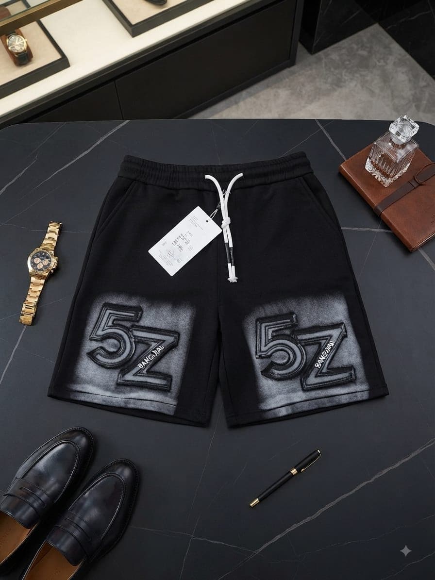 Black stone-washed shorts with large 5Z embroidery on faded panels, styled flat lay with watch, shoes and accessories.