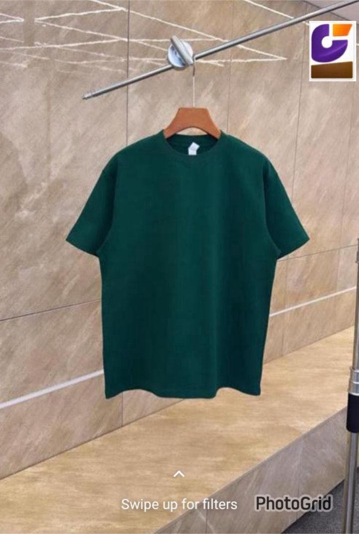 Dark green oversized plain t-shirt hanging on wooden hanger.