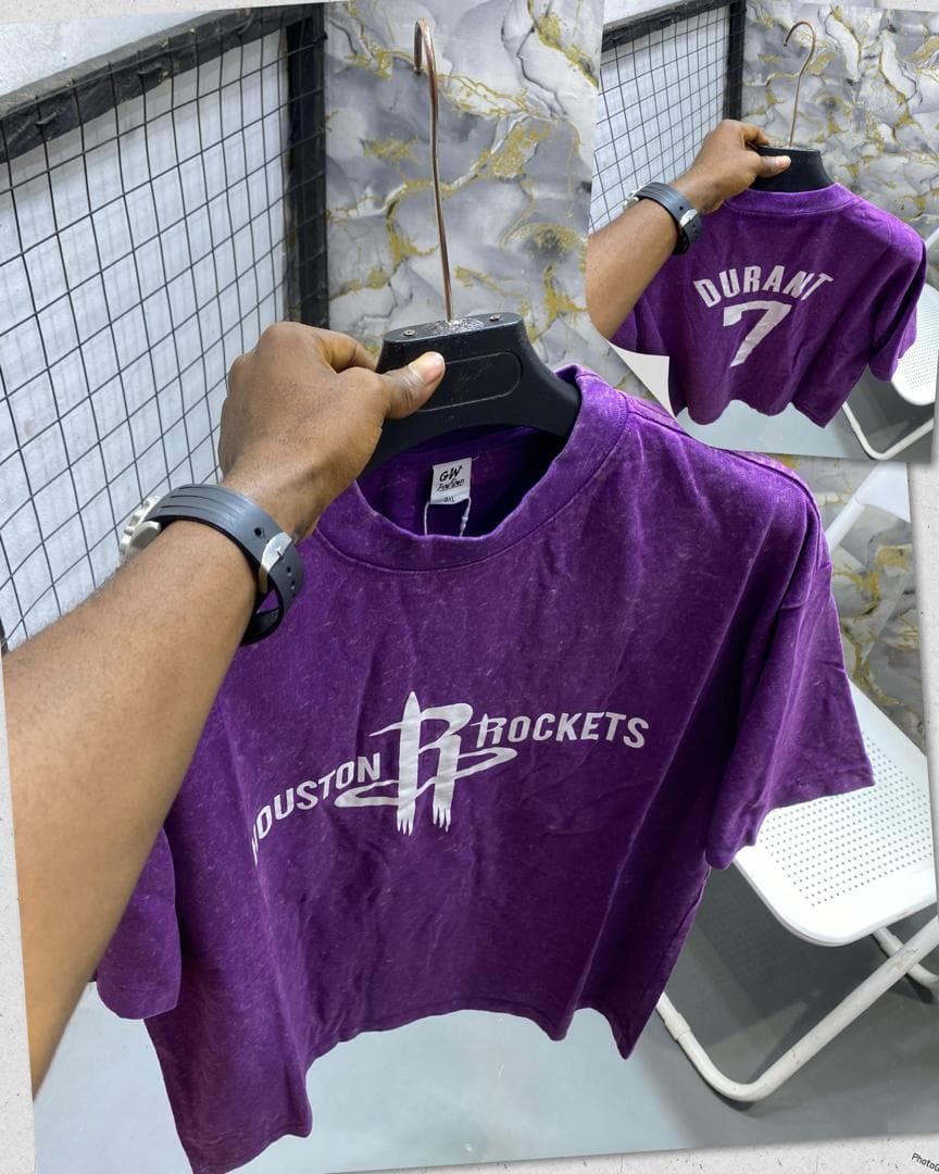 Purple stonewash t-shirt with Houston Rockets graphic held on hanger showing front and back.