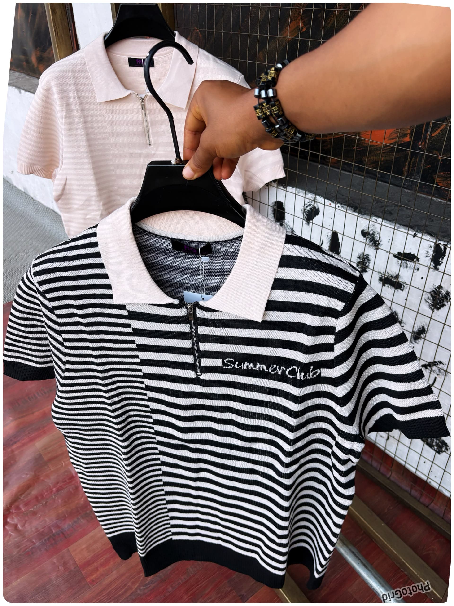 Black and white striped half-zip polo shirt with Summer Club embroidery held on hanger.