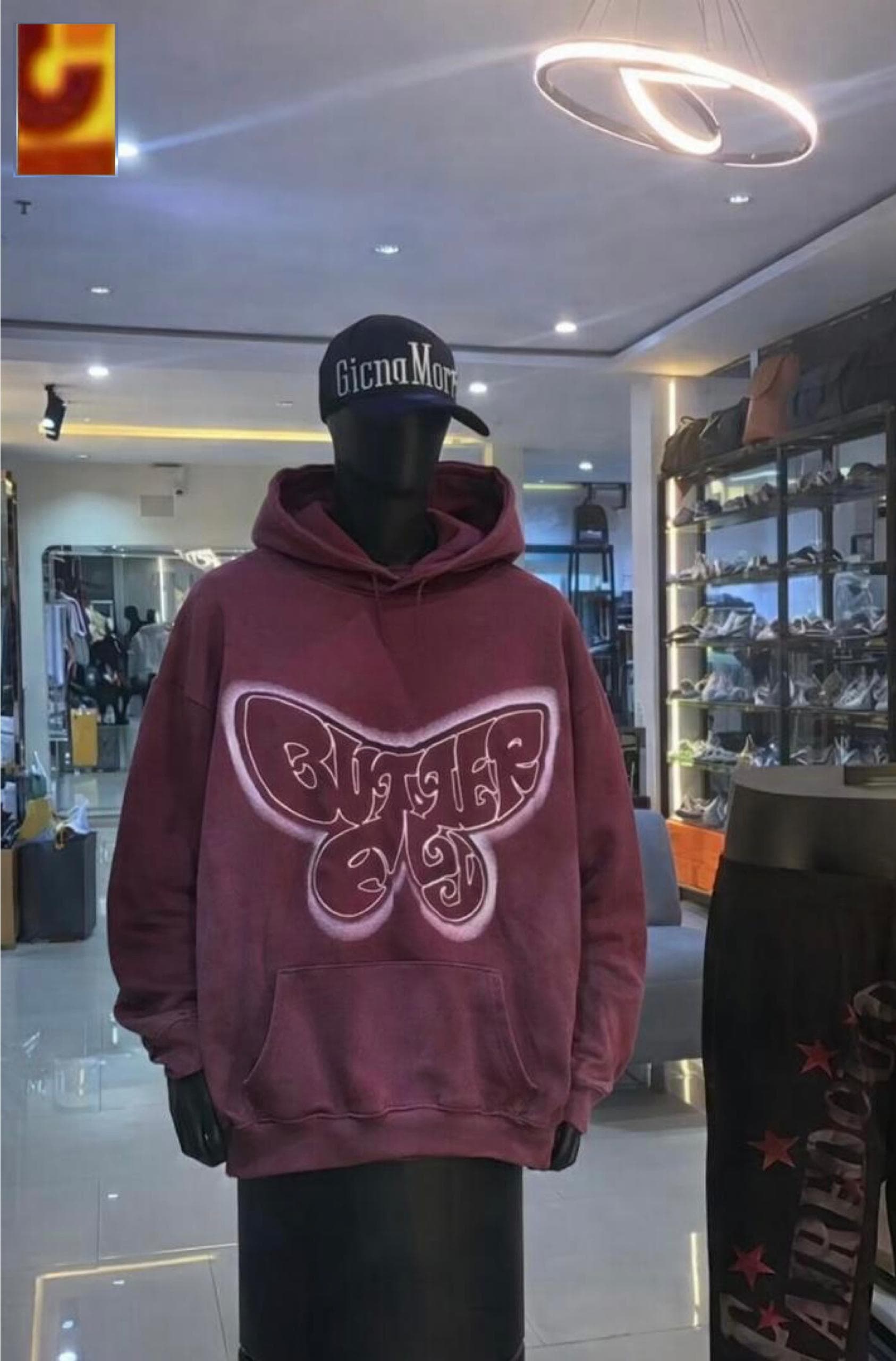 Mannequin wearing oversized burgundy hoodie with large white butterfly graphic on chest.