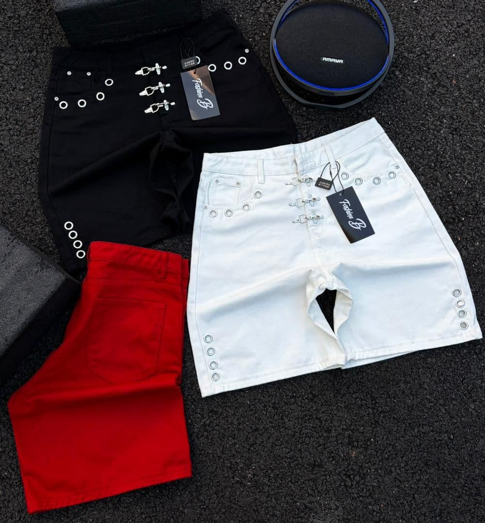 Flat lay of black, white, and red grommet denim shorts with accessories.
