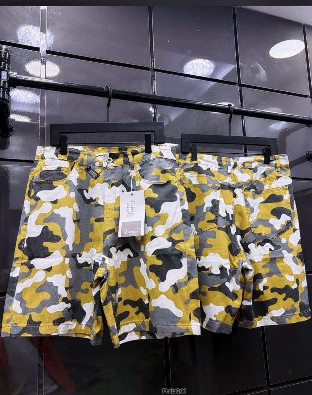 Yellow gray white camo print denim shorts on display hangers.
