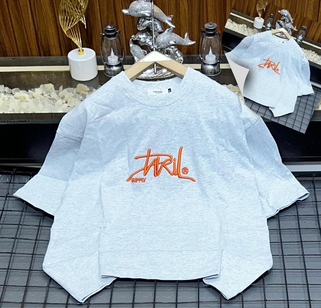 Light gray oversized t-shirt with orange JRIL SUPPLY script logo, flat lay with hanger and inset view.
