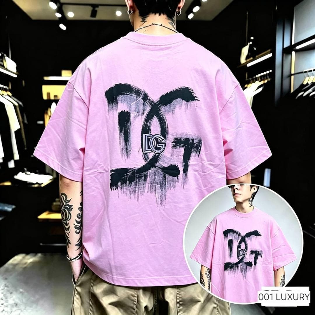 Man from back in pink oversized t-shirt with large black DG brush splatter graphic on back.