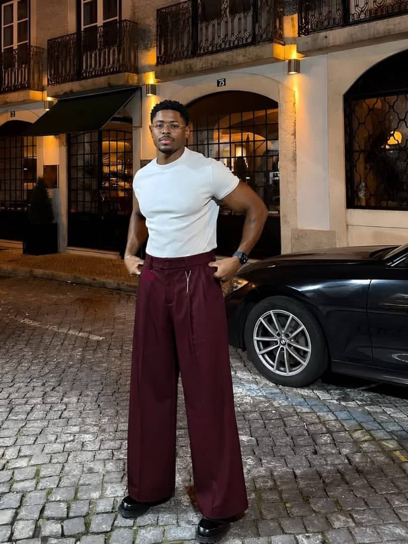 Model in burgundy wide leg pleated flare trousers with white t-shirt.