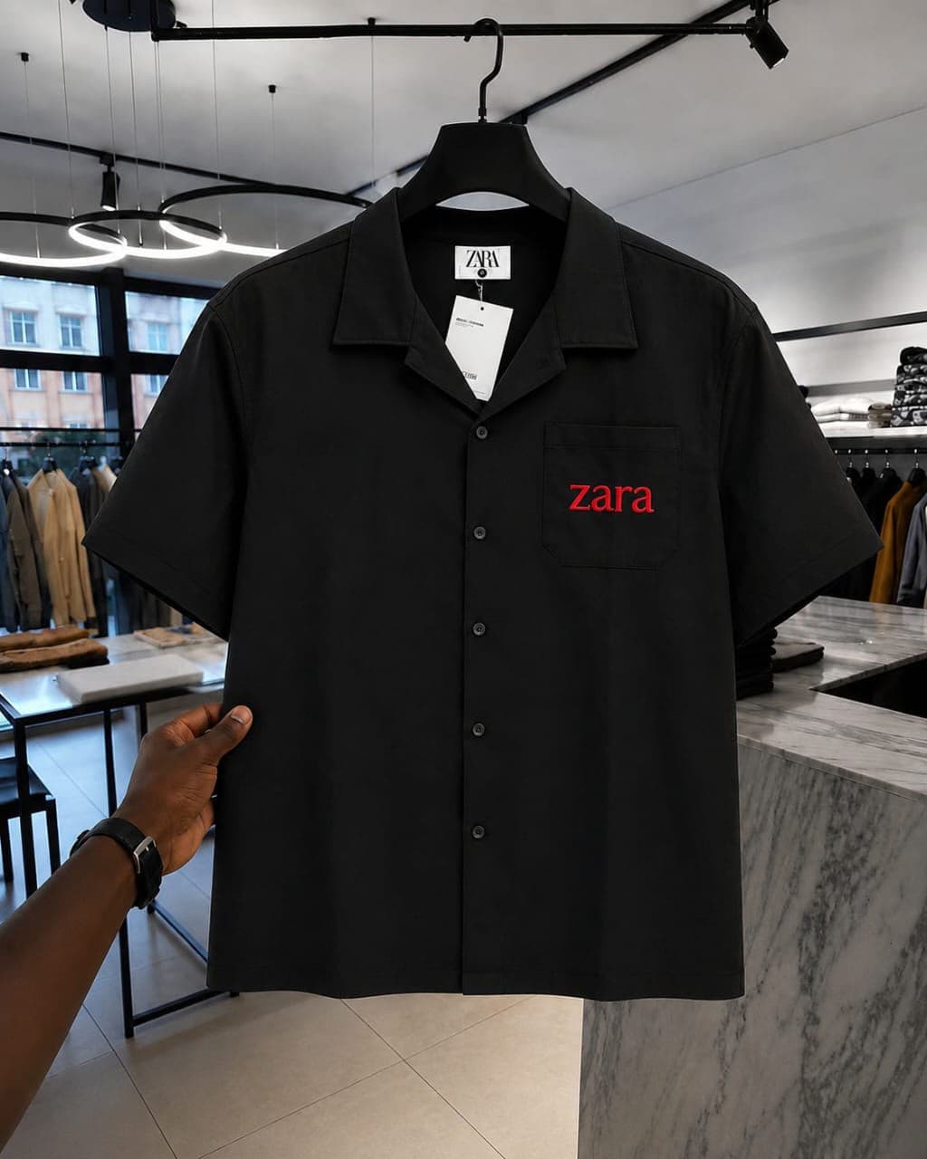 Black short-sleeve button-up shirt with red 'zara' embroidery on chest pocket.