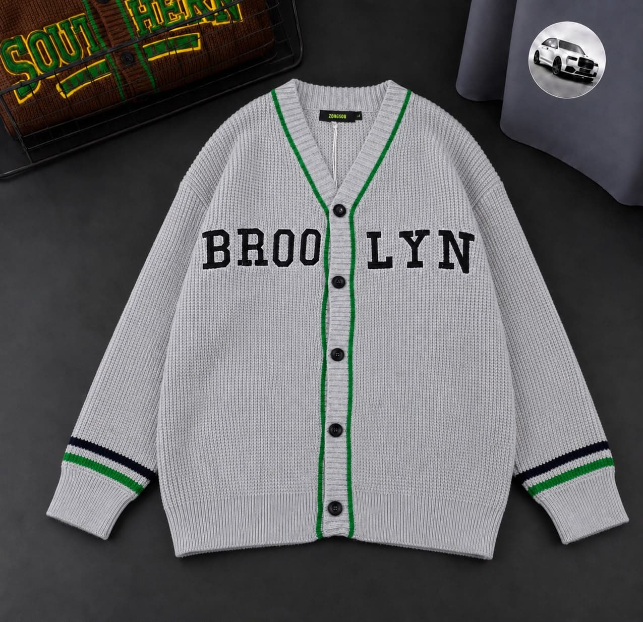 Gray Brooklyn cardigan with green trim and embroidery shown flat.