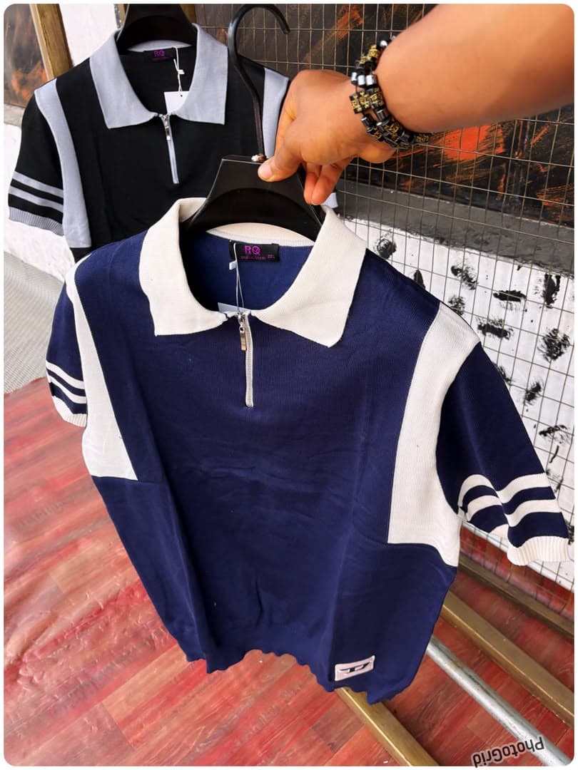 Navy and white colorblock knit polo in foreground with black and gray version behind.