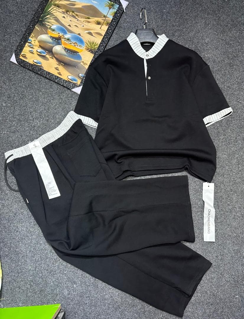 Black two-piece set with striped trim on short-sleeve top and drawstring pants.