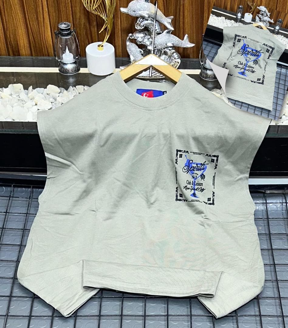 Beige Spirits graphic sleeveless sweatshirt on hanger with back inset.