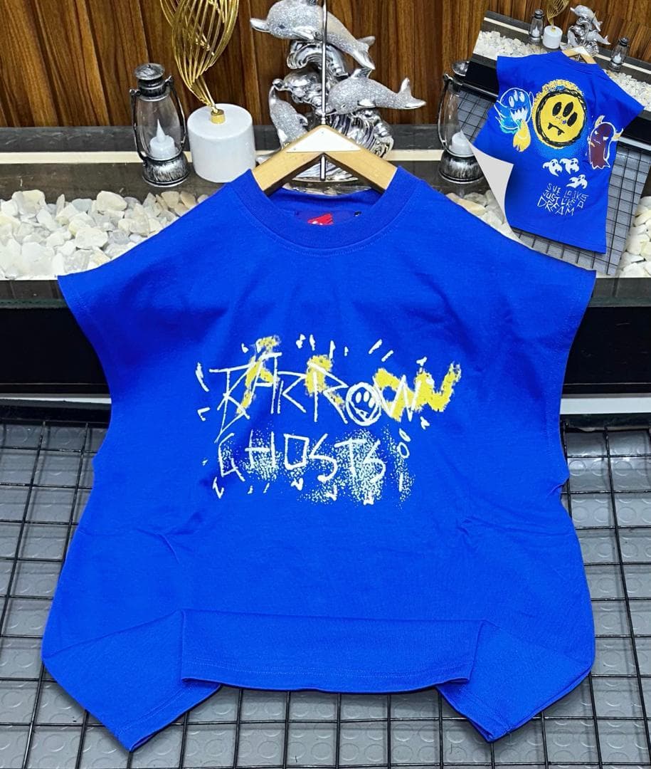 Blue oversized sleeveless top with yellow and white graffiti print on chest.