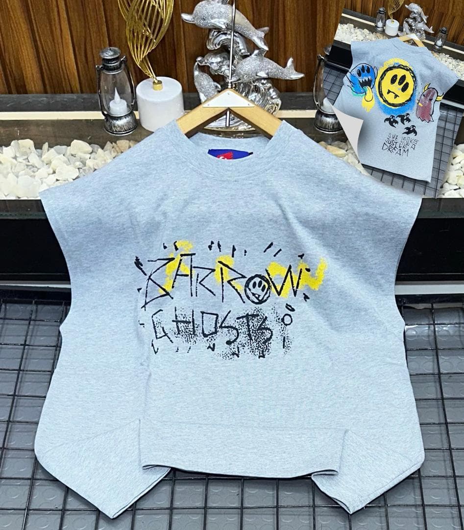 Gray oversized sleeveless top with black and yellow graffiti print on chest.