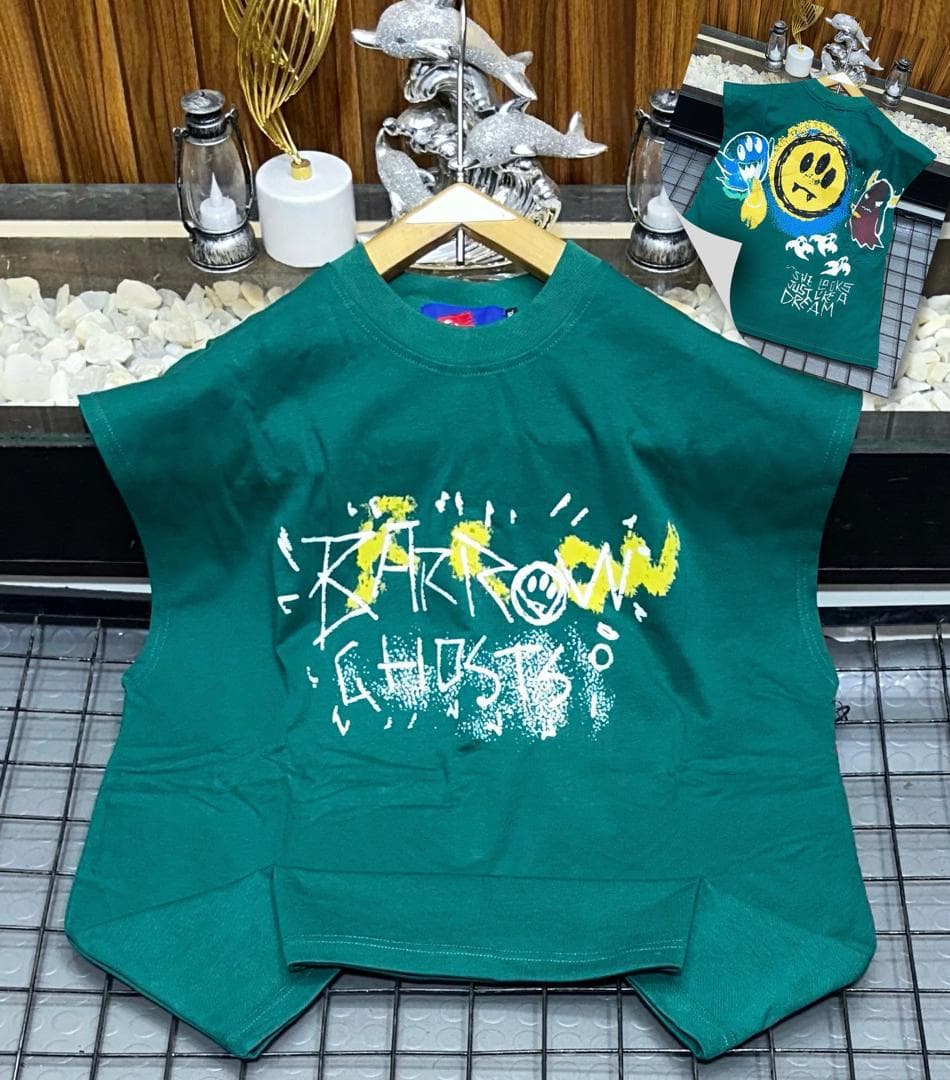Green oversized sleeveless top with yellow and white graffiti print on chest.