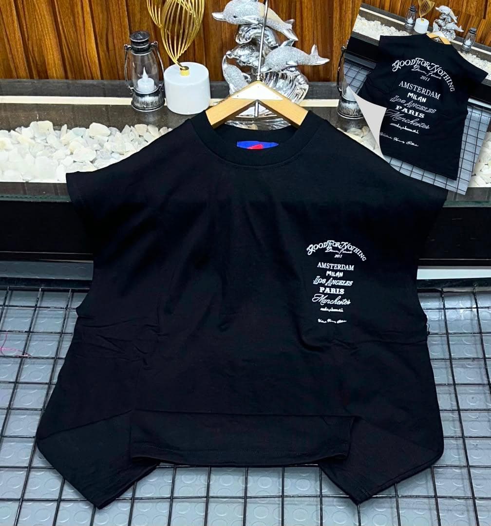 Black oversized sleeveless top with white city names graphic on chest.