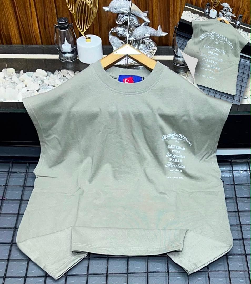 Olive oversized sleeveless top with white city names graphic on chest.