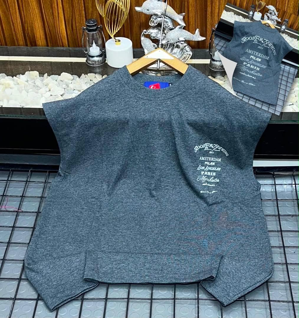 Gray oversized sleeveless top with white city names graphic on chest.