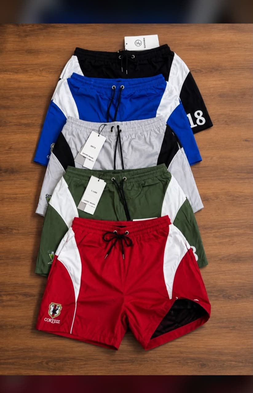 Stacked view of five color variations of panel colorblock shorts on wood.