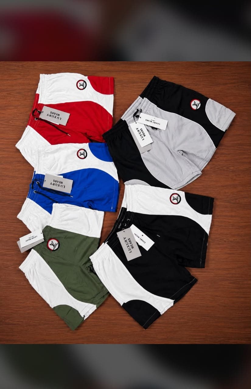 Five different colorways of curved colorblock cargo shorts laid out on wooden surface.