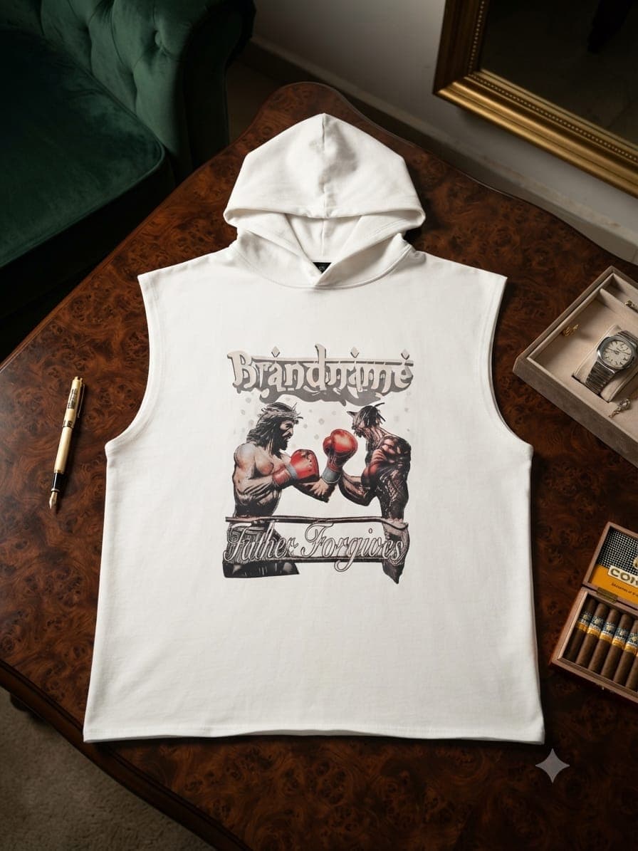 White sleeveless hoodie with Father Forgives boxing graphic laid on wooden table.