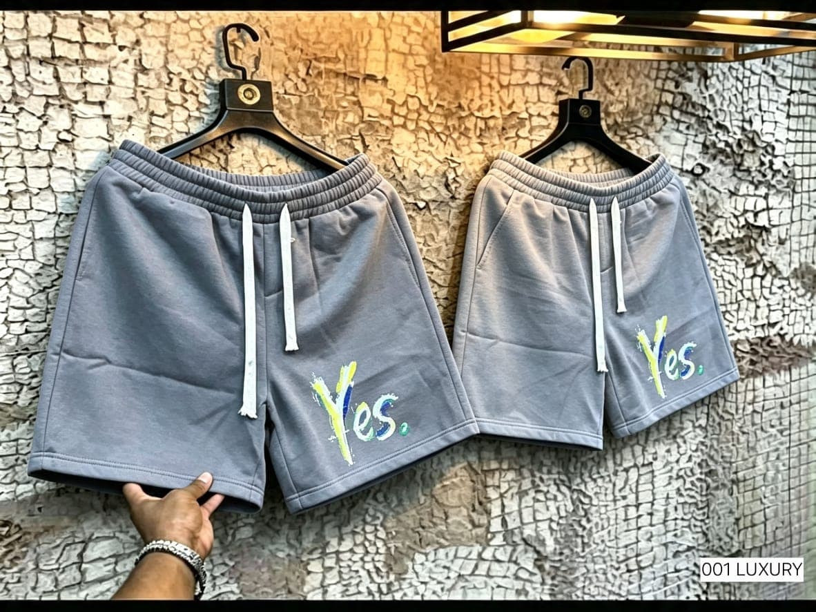 Gray fleece shorts with Yes embroidery on leg, held by hand.