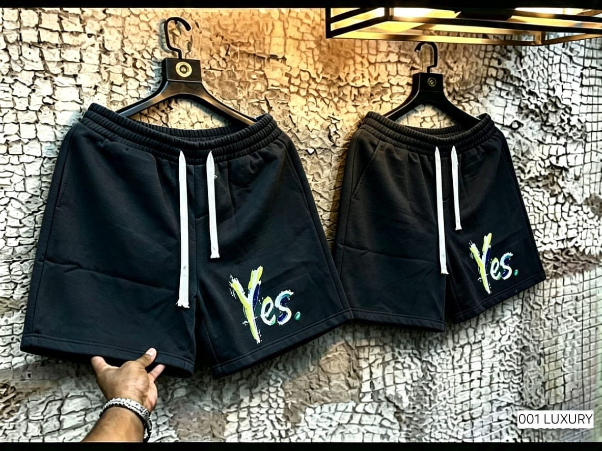 Black unisex shorts with colorful Yes embroidery displayed on hooks.