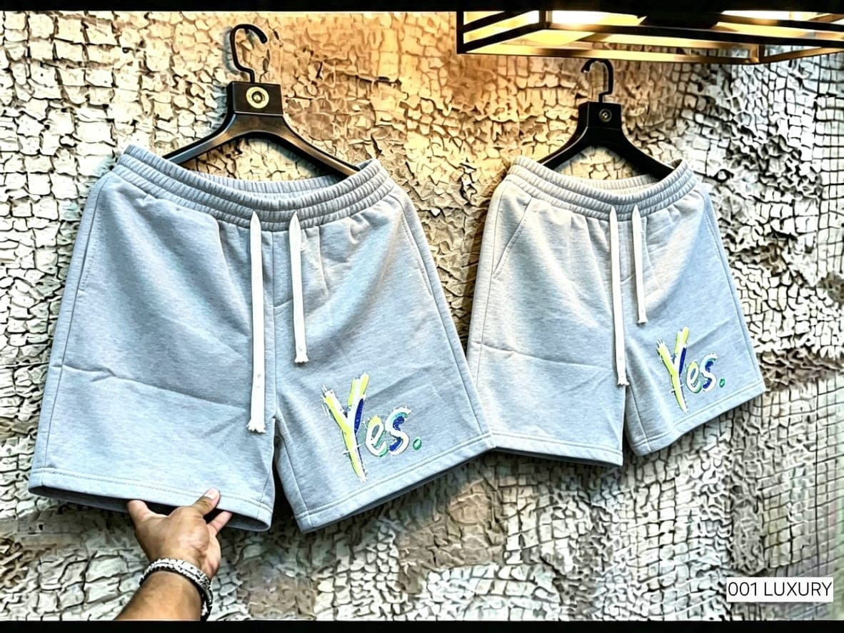 Light gray shorts with colorful Yes embroidery hanging on wall.