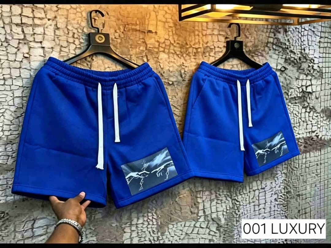 Blue fleece shorts with hand lightning graphic hanging on wall.