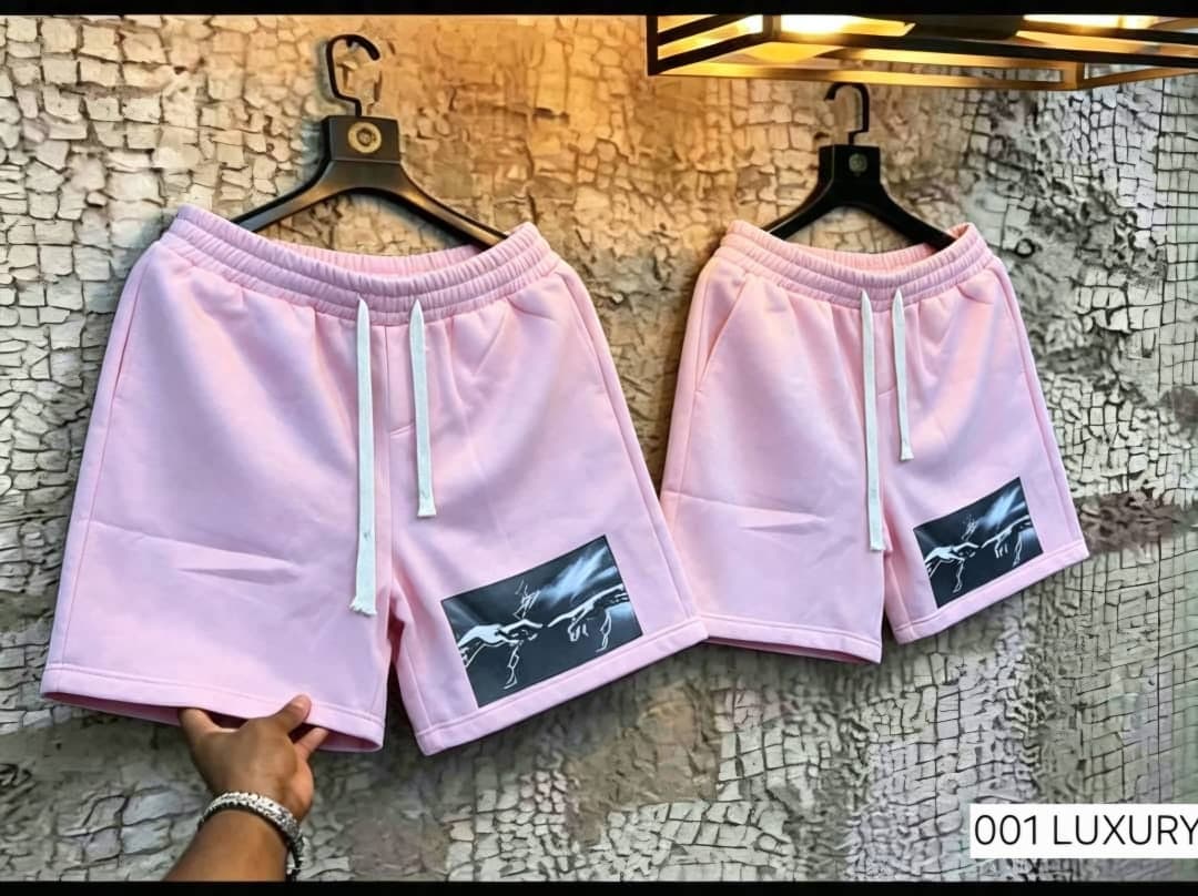 Pink unisex shorts with graphic print on leg, shown hanging.