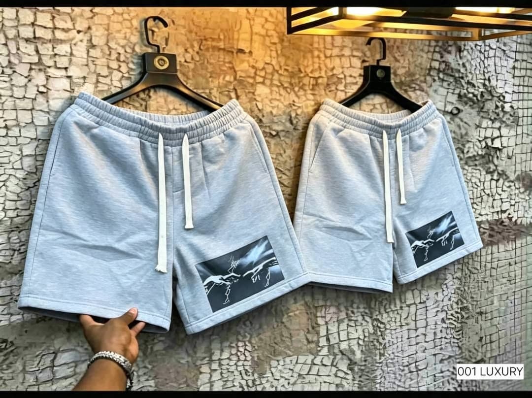 Light gray fleece shorts with hand and lightning print hanging on hooks.