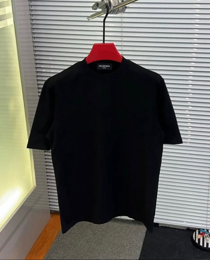 Black plain T-shirt with Balenciaga neck label on red hanger.