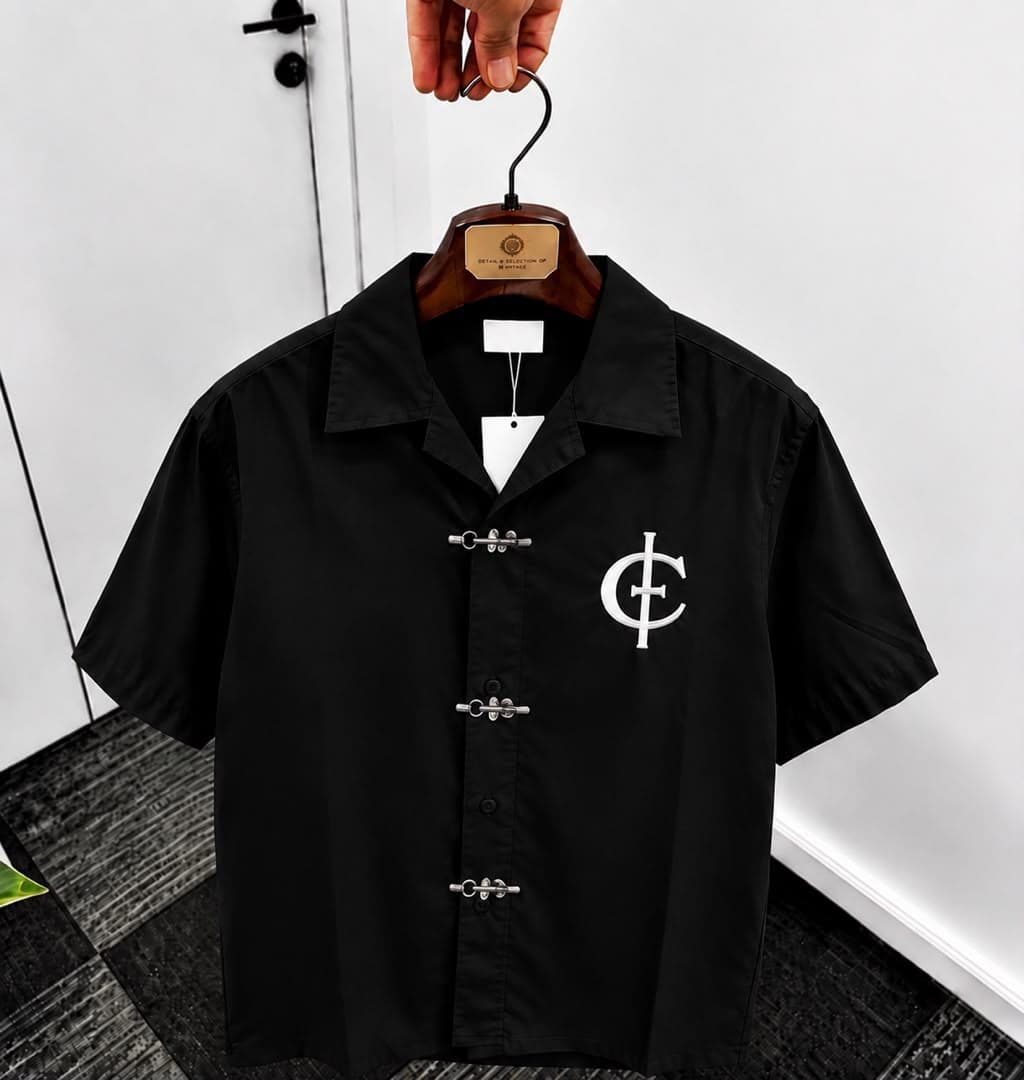 Black unisex short sleeve shirt with toggle buttons and white chest logo.