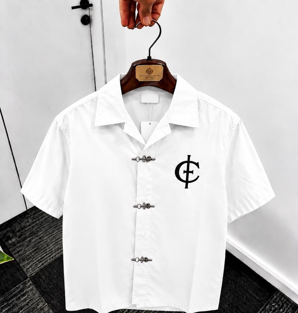 White unisex short sleeve shirt with toggle buttons and black chest logo.