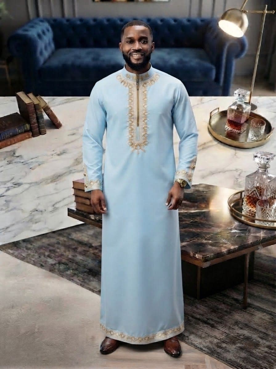 Model wearing light blue embroidered kaftan with gold trim.