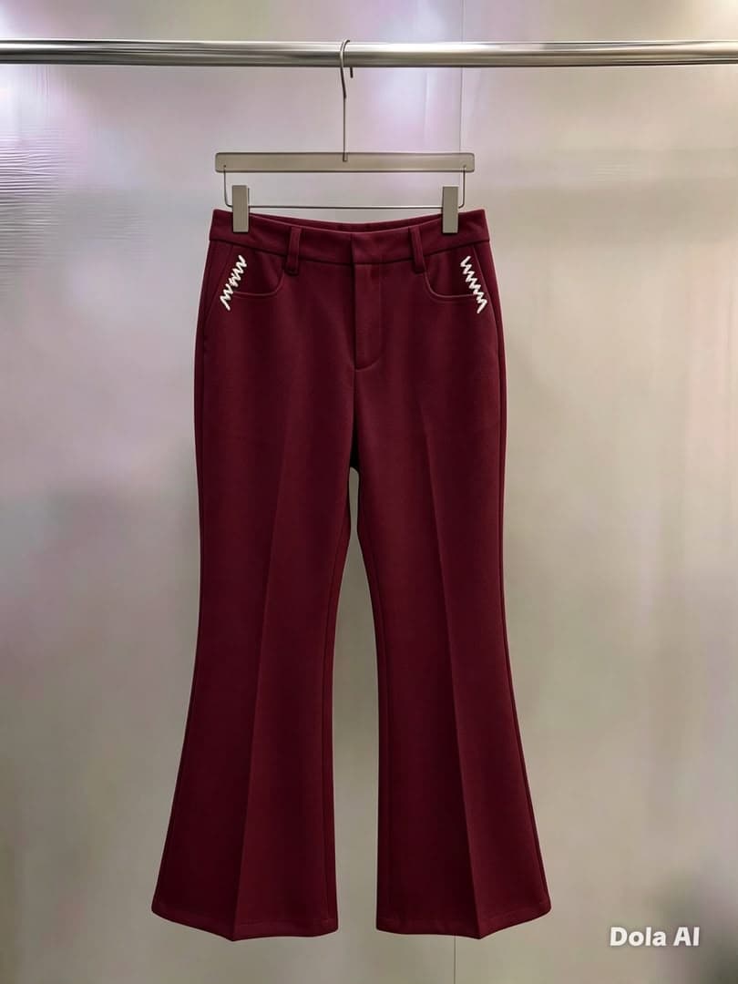 Burgundy flare trousers with white zigzag pocket embroidery, hanging view.