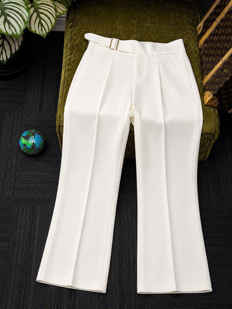 White high-waisted flare trousers with belt, flat lay view.