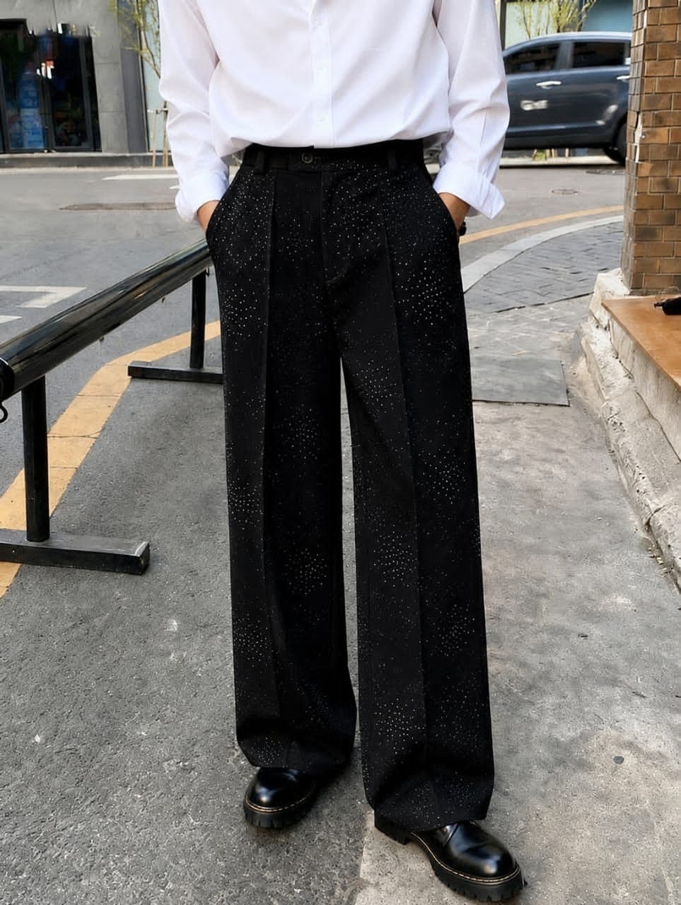 Model wearing black embellished wide-leg flare trousers with hands in pockets.
