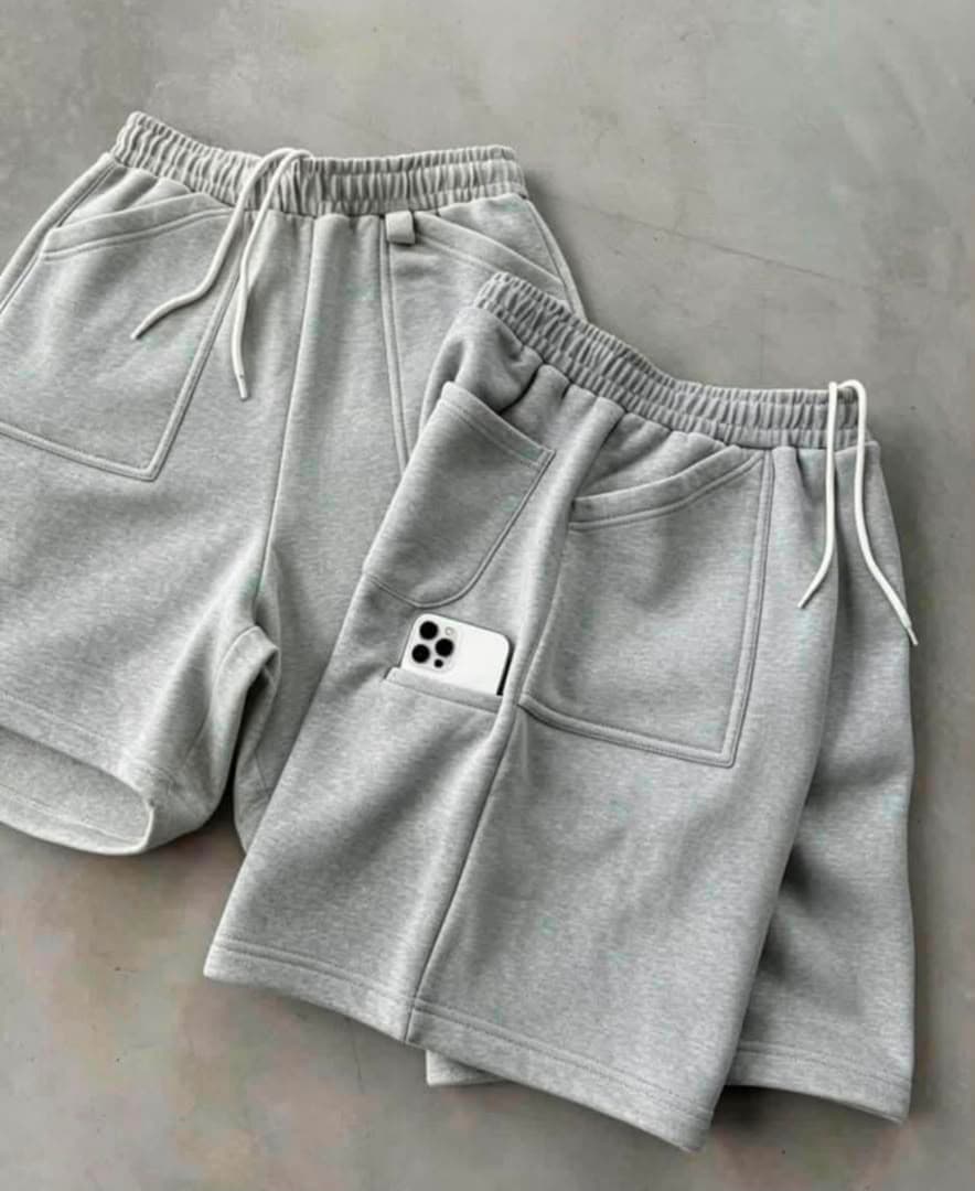 Light gray fleece shorts laid flat with elastic waist, drawstring and phone in pocket.