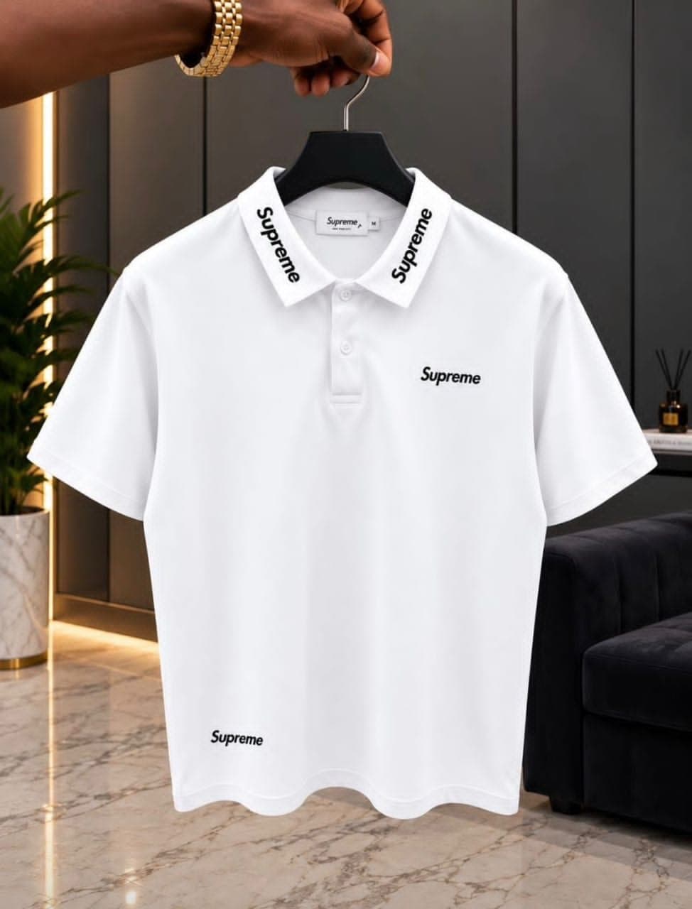 White Supreme polo shirt on hanger in modern interior.